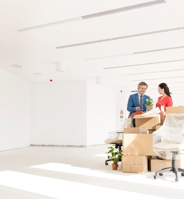 Business people discussing while standing by cardboard boxes in new office